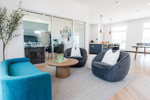 a living room with blue chairs and a table at Converge NW, Waukee, IA 50263  