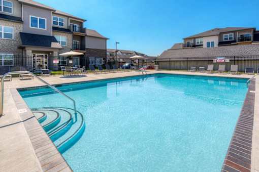 A swimming pool surrounded by a wooden deck and a fence. at Stonegate Crossing Apartments, IOWA