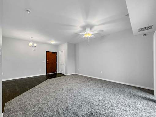 A room with a carpeted floor and a ceiling fan. at Stonegate Crossing Apartments, IOWA