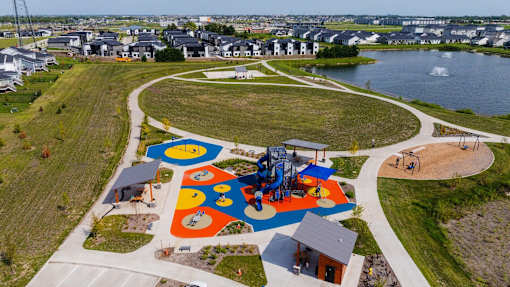 an aerial view of a playground in a park next to a lake at Rialto Townhomes Apartments, Iowa