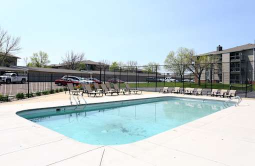 a swimming pool with chairs and a fence around it at Penbrooke Place Apartments, Sioux Falls, SD