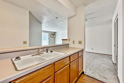 A kitchen with wooden cabinets and a white sink at Penbrooke Place Apartments, Sioux Falls