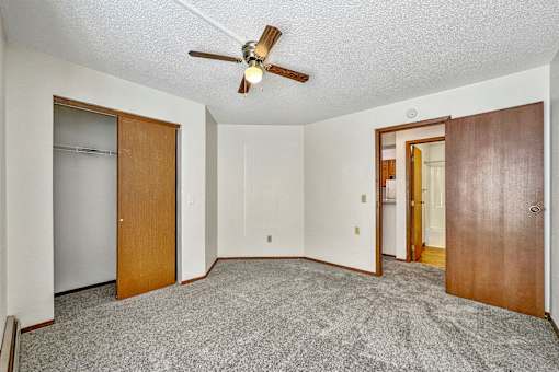 an empty living room with a ceiling fan and a door to a closet at Penbrooke Place Apartments, South Dakota, 57106