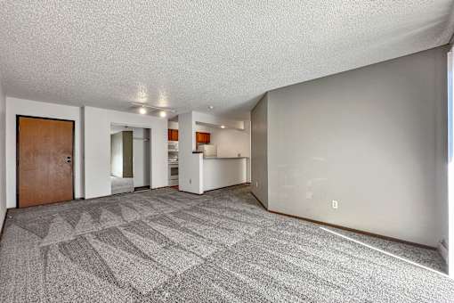 the living room and kitchen of an apartment with a carpeted floor at Penbrooke Place Apartments, South Dakota