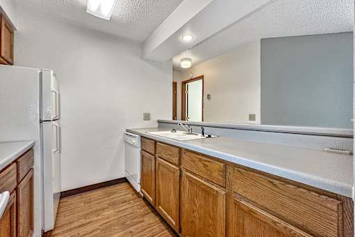A kitchen with wooden cabinets and a white fridge at Penbrooke Place Apartments, Sioux Falls, SD, 57106