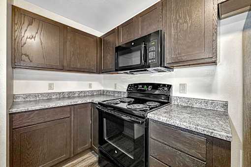 a kitchen with black appliances and wood cabinets at Penbrooke Place Apartments, South Dakota, 57106