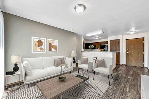 A living room with a white sofa, a coffee table, and a dining area in the background at Penbrooke Place Apartments, Sioux Falls, 57106