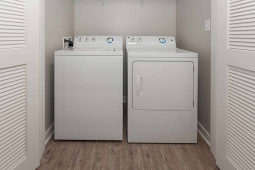 A white washing machine and dryer in a small laundry room at Spaulding Lofts Apartments, IA, 50112