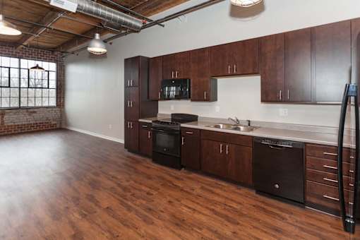 A kitchen with wooden floors and dark brown cabinets at Spaulding Lofts Apartments, Grinnell, IA