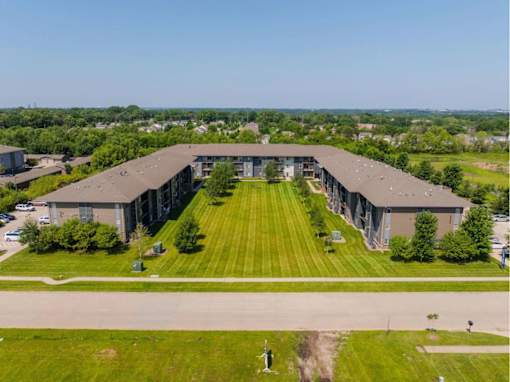 A large, modern building with a long, wide lawn in front.