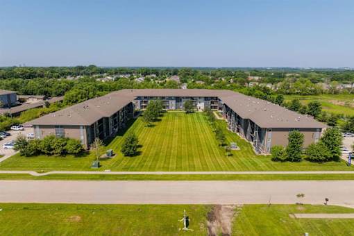 A large, modern building with a long, wide lawn in front.