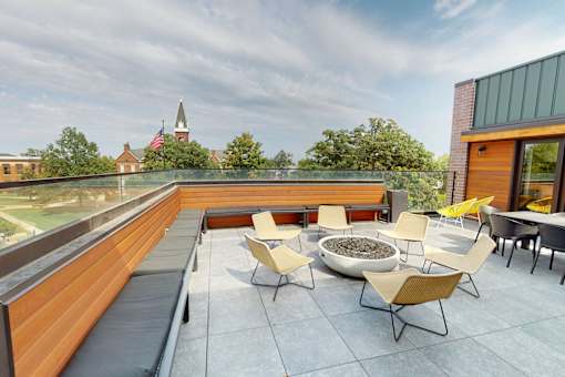 a rooftop terrace with chairs and tables and a fire pit at Canary Lofts, Des Moines, 50311