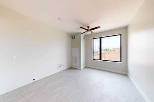an empty living room with a ceiling fan and a large window at Canary Lofts, Des Moines, IA
