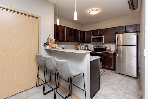 spacious kitchen with stainless steel appliances and a bar with three stools at Lake Shore Apartments, Ankeny
