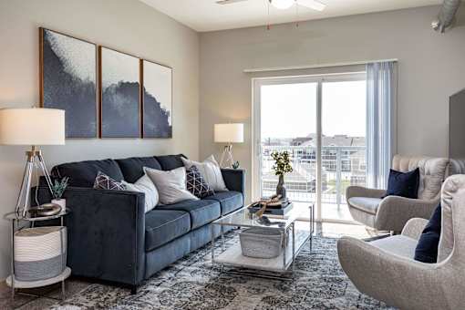 a living room with a blue couch and a glass coffee table at Lake Shore Apartments, Ankeny, Iowa