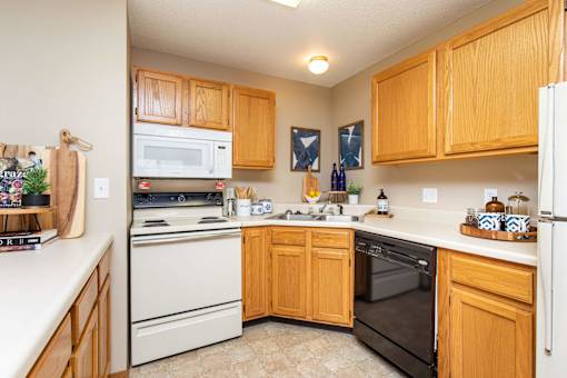 A kitchen with wooden cabinets and white appliances at Lake Shore Park, Ankeny, 50021
