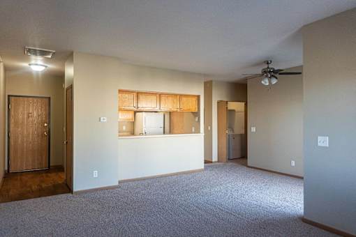 an empty living room with a kitchen and a ceiling fan at Sunrise Meadows, Waukee, IA