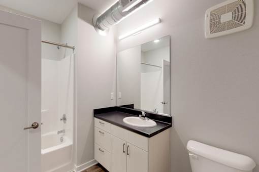A bathroom with a sink, mirror, and toilet at Vue Apartments, IA, 50309
