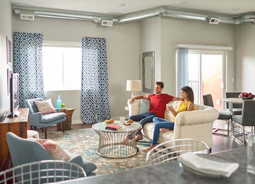 a man and woman sitting on a couch in a living room at Vue Apartments, Iowa, 50309