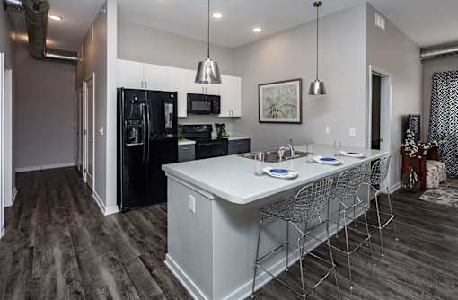 A modern kitchen with a black fridge and white countertops at Vue Apartments, Iowa