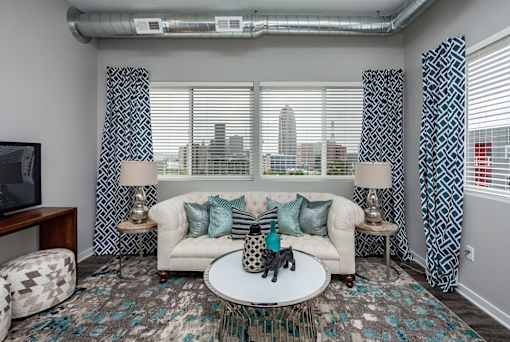 a living room with a couch and a table in front of a window at Vue Apartments, IA, 50309