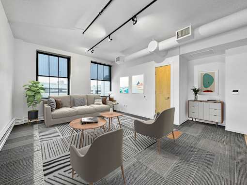 A modern living room with a grey carpet and a brown chair at The Des Moines Building Apartments, Des Moines, Iowa