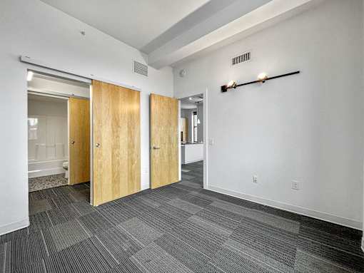 A hallway with a carpeted floor and a white wall at The Des Moines Building Apartments, Des Moines, IA
