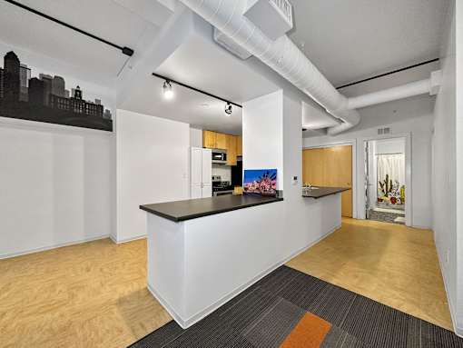 A white reception desk with a black counter top is in the middle of a room with wood flooring at The Des Moines Building Apartments, Des Moines