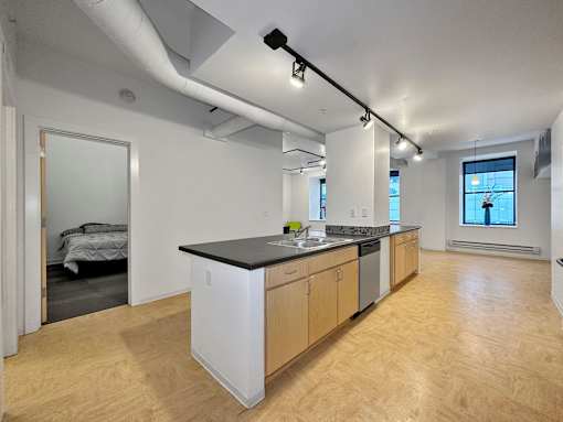 A kitchen with wooden floors and a black countertop at The Des Moines Building Apartments, IA, 50309