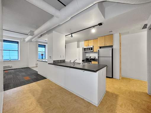 A kitchen with a white island and wooden cabinets at The Des Moines Building Apartments, Iowa, 50309