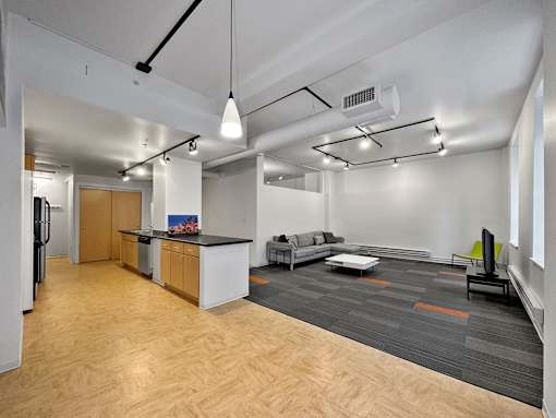A modern open plan office space with a kitchen area at The Des Moines Building Apartments, Des Moines, IA