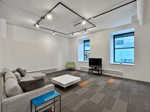 A living room with a grey couch, a white coffee table, and a television at The Des Moines Building Apartments, IA, 50309