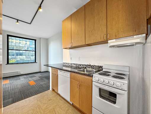 A kitchen with a white stove and wooden cabinets at The Des Moines Building Apartments, Des Moines, IA, 50309
