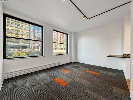 A room with a grey carpet and two windows at The Des Moines Building Apartments, Des Moines, Iowa