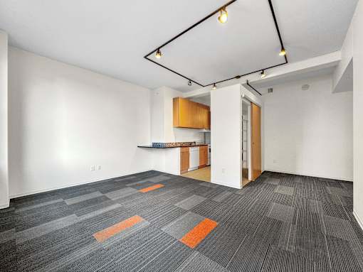 A room with a grey carpet and a wooden cabinet at The Des Moines Building Apartments, Des Moines, IA