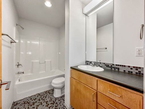 A bathroom with a white toilet, a white sink, and a white bathtub at The Des Moines Building Apartments, Des Moines, Iowa