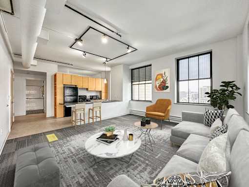 A living room with a grey couch, a white coffee table, and a yellow chair at The Des Moines Building Apartments, Des Moines, Iowa