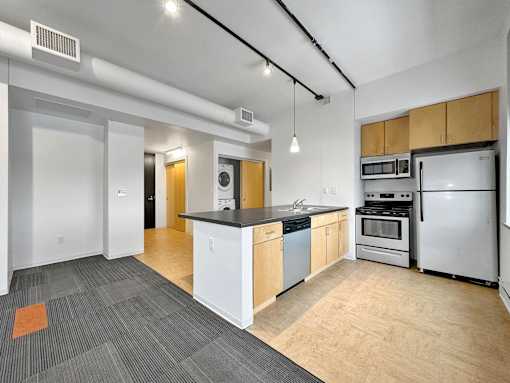 A kitchen with white appliances and wooden cabinets at The Des Moines Building Apartments, Iowa