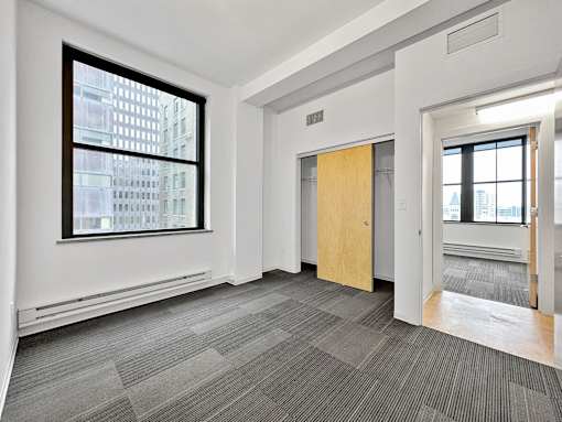 A room with a grey carpet and a wooden door at The Des Moines Building Apartments, Des Moines