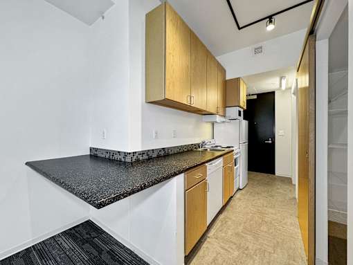 A kitchen with white cabinets and a black counter top at The Des Moines Building Apartments, Des Moines