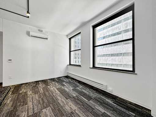 A room with a window and a wall-mounted air conditioner at The Des Moines Building Apartments, Des Moines