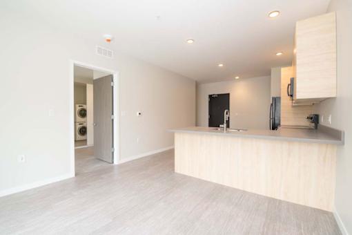 a white kitchen with a large island and a door to a laundry room at Rowat Lofts, Des Moines Iowa   