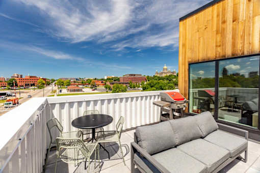 a balcony with a couch and a table and chairs at Rowat Lofts, Des Moines, 50309  