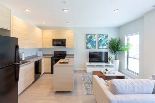 a living room with a kitchen and a couch at Rowat Lofts, Des Moines, IA 50309  
