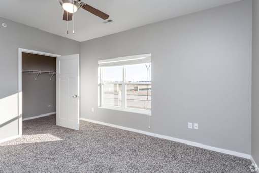 A room with a ceiling fan and a window overlooking a parking lot at The Barclay Apartments, Altoona, IA, 50009