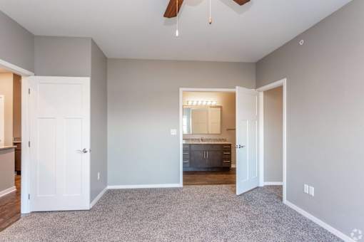 a bedroom with a carpeted floor and a door to a bathroom at The Barclay Apartments, Altoona, 50009