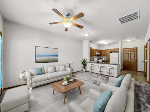A living room with a white couch, a coffee table, and a ceiling fan.at Cornerstone Commons, Johnston, IA 50131  