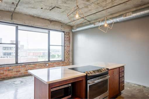 Kitchen with a brick wall and a large window at Clemens Building, Des Moines, IA