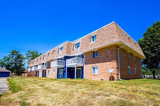 A red brick building with a balcony on the second floor at The Hampton Meadows Apartments, IA,50315