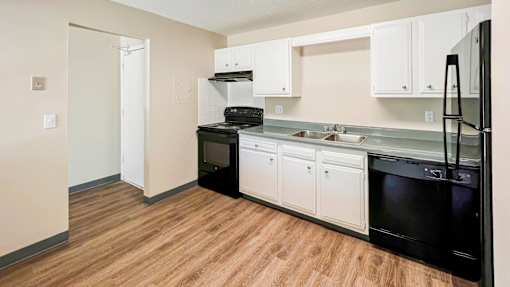 A kitchen with black appliances and white cabinets at The Hampton Meadows Apartments, Des Moines, IA, 50315